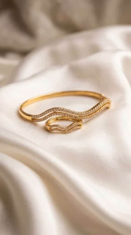 Gold zigzag bangle and ring set with crystal stone clusters on satin fabric